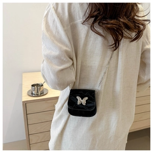 Detail of black faux crocodile skin mini bag with silver butterfly metal buckle