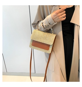 Detail of straw handbag featuring elegant pearl handle and brown leather flap closure