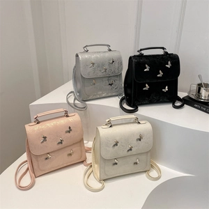 Metallic wrinkled mini backpacks with 3D butterfly accents in four colors on steps