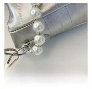 Detail of silver embossed leather bag with pearl chain strap and rhinestone accents