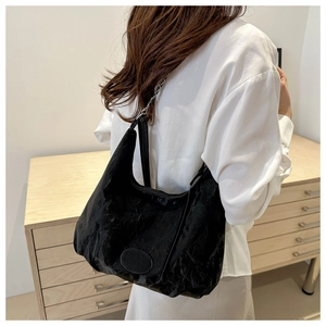 Detail of a large black tote bag with textured fabric and metallic chain shoulder strap