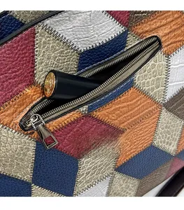 Close-up of a side zipper pocket on a colorful leather tote bag holding a lipstick