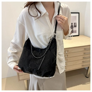 Detail of black crescent shoulder bag with silver chain and long strap on a model