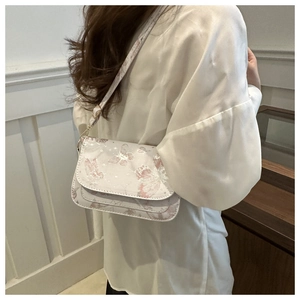 Close-up detail of soft pink butterfly pattern on women's stylish shoulder bag