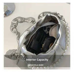 Internal capacity of silver cloud bag showing phone, wallet and cosmetics inside