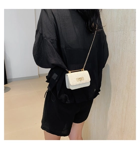 Rear view of model wearing a woven mini chain crossbody bag with golden lock