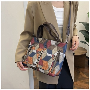 Detailed close-up of a vintage patchwork tote bag on a model wearing a brown blazer
