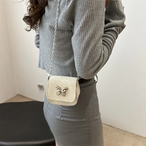 Chic cream crossbody bag with silver butterfly buckle and metallic chain strap