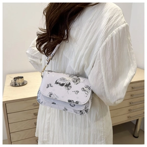 Detail of white PU shoulder bag featuring black ink butterfly print and gold hardware