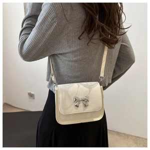 Detail view of cream square crossbody bag with marble texture and silver metal bow