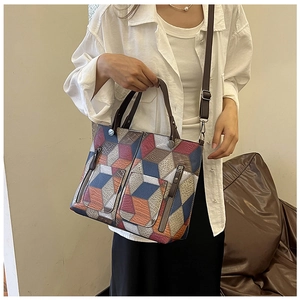 Detail shot of multi-color geometric patchwork tote bag with metal zippers and shoulder strap