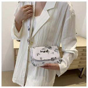 Close-up of white butterfly print crossbody bag with gold hardware and flap detail