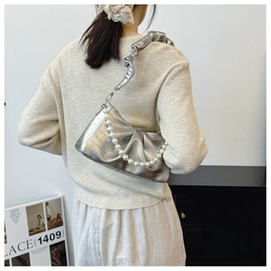 Detail of silver metallic shoulder bag with pearl chain and ruffled strap on model