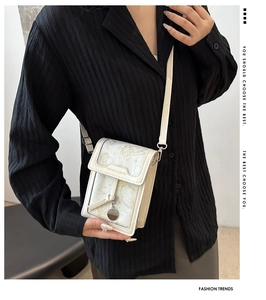 Detail of white mini crossbody phone bag with golden butterfly print and metallic clasp