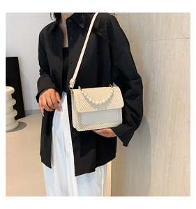 Detail of summer straw crossbody bag with elegant pearl handle and cream leather trim