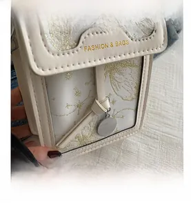Close-up of beige jacquard phone bag featuring gold star embroidery and metal pendant