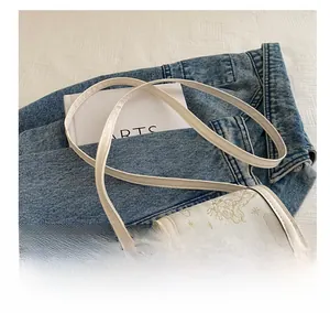 Detail of cream mini crossbody bag with gold butterfly embroidery and thin strap
