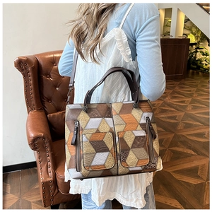 Detail of geometric patchwork tote bag with zipper pockets in an indoor setting
