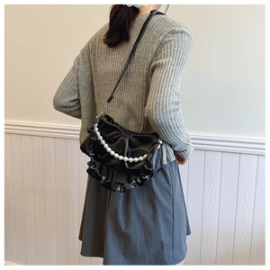 Détail du sac nuage plissé noir avec grande chaîne de perles blanches et cuir PU brillant