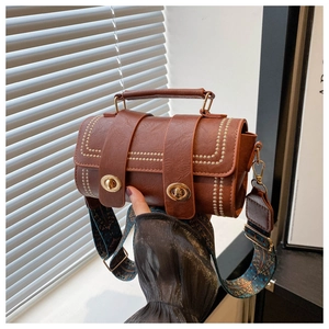 Détails du sac cylindre en cuir caramel avec surpiqûres blanches et bandoulière tissée