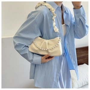 Close-up of off-white ruched underarm bag with decorative pearl chain and ruffled strap