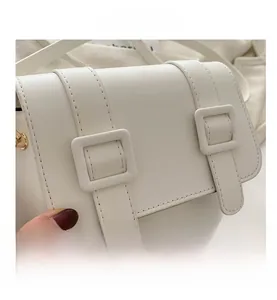 Detailed close-up of white faux leather texture and square buckle on the modern saddle bag