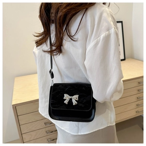 Detail of black velvet crossbody bag with silver butterfly buckle worn by a model