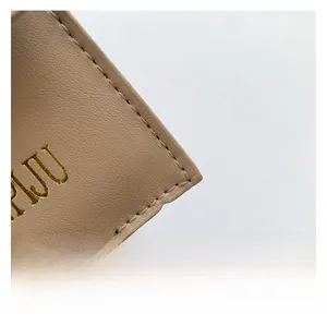 Détails du sac en cuir beige avec logo PJU doré et coutures artisanales précises
