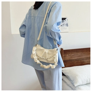 Détail du sac à bandoulière plissé blanc crème avec chaîne perlée et sangle réglable