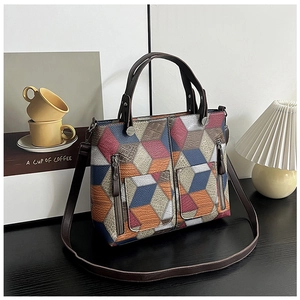 Close-up of geometric patchwork tote bag with dual zipper pockets and leather texture
