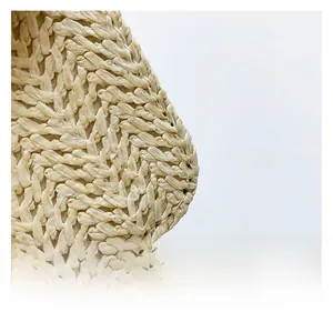 Détail macro de la texture en paille tressée à la main d'un sac bandoulière moderne crème