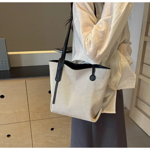 Detail der Canvas-Beuteltasche aus strukturiertem Stoff mit schmalen schwarzen Lederriemen