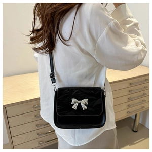 Detail of silver bow metal ornament on a black vintage crossbody small square bag