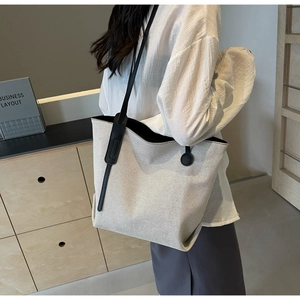 Detail of canvas tote bag with black leather straps and premium textured fabric surface