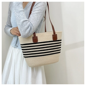 Détail d'un sac cabas en paille tissée avec rayures noires et anses en cuir marron