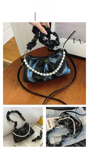 Détail du sac baguette noir en similicuir avec chaîne en perles et anse froncée