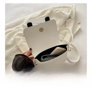Interior capacity show of white saddle bag with magnetic closure and lychee grain texture