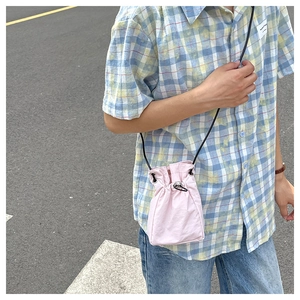 Close-up of pink drawstring mini crossbody bag with black rope strap on model