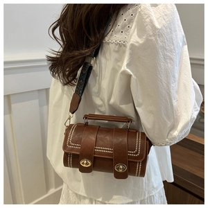 Detail of vintage brown cylinder crossbody bag with golden twist locks and jacquard strap