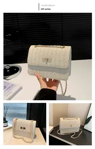 Détail du sac beige tissé avec fermoir doré et bandoulière en chaîne sur un bureau