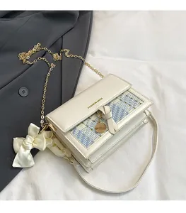 Detail of cream tweed crossbody bag with golden chain and white satin bow decoration