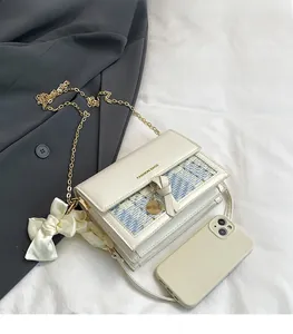 Size comparison of white plaid tweed crossbody bag next to a smartphone