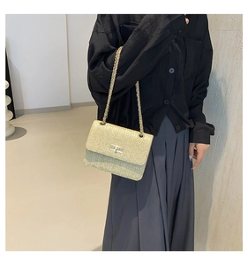 Détail du sac bandoulière en paille beige avec texture tissée en V et chaîne dorée