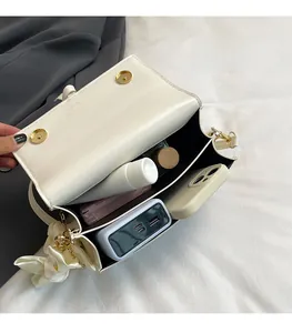 Detail shot of white crossbody bag with dual-layer storage for phone and makeup items