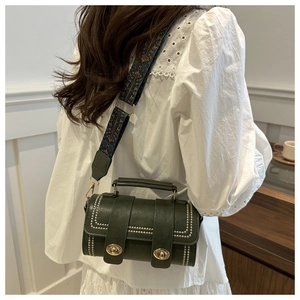 Detail of dark green cylinder bag with vintage gold lock and ethnic embroidery strap
