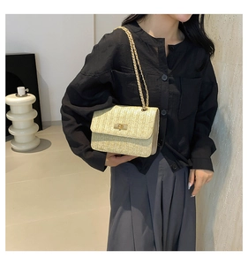 Détail du sac à bandoulière en paille tressée beige avec fermoir rotatif et chaîne dorée