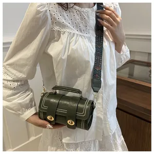 Détail du sac cylindrique vert foncé avec rivets blancs et bandoulière ethnique