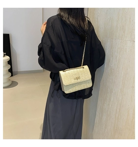 Detail showing beige woven texture with gold chain strap and lock on a square crossbody bag