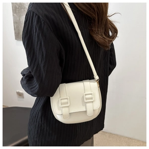 Lifestyle shot of a white saddle crossbody bag worn by a model against a minimalist wall