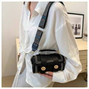 Detail of black leather handbag featuring golden studs and bohemian wide shoulder strap